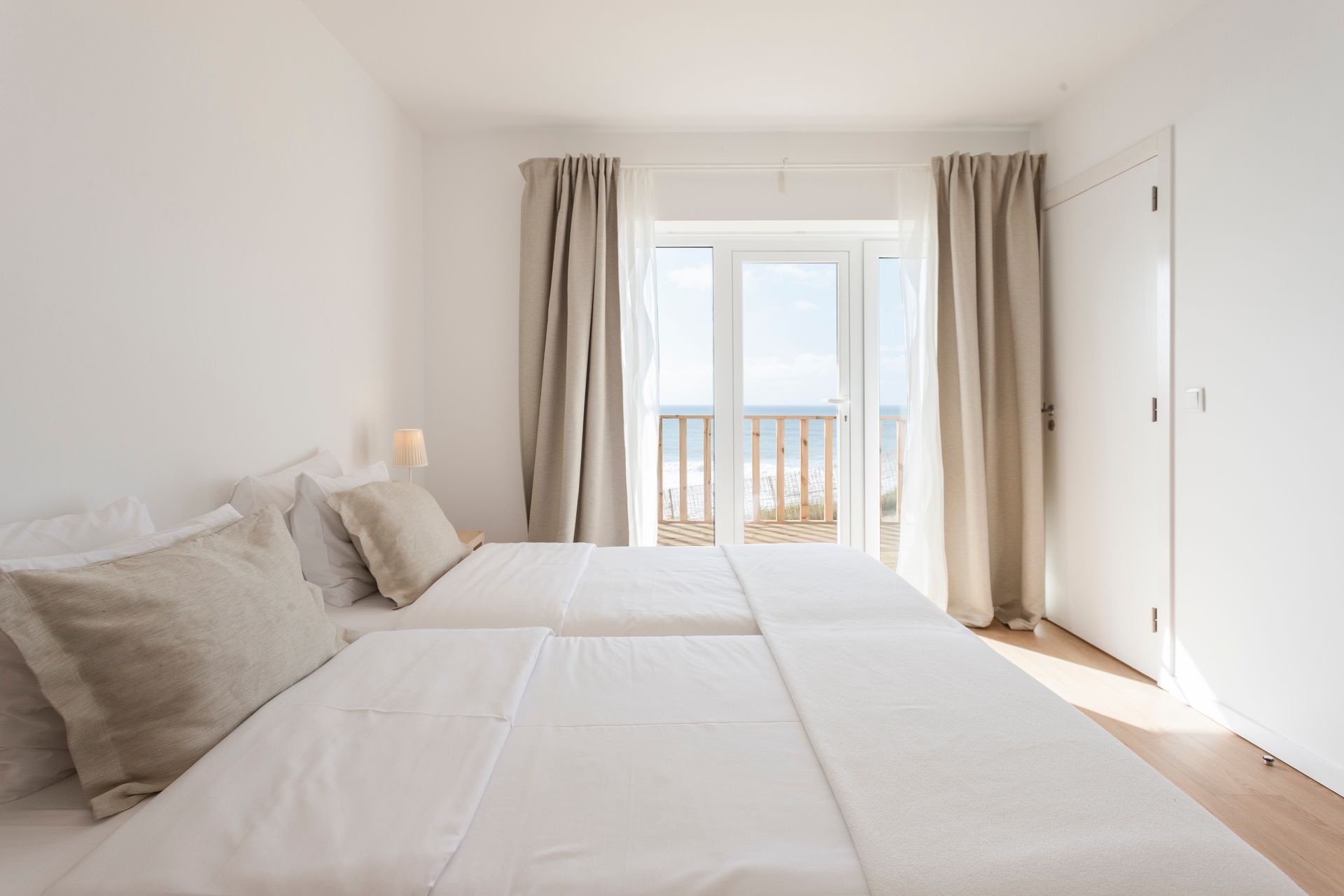 a bedroom with two beds and a balcony with a view of the ocean .