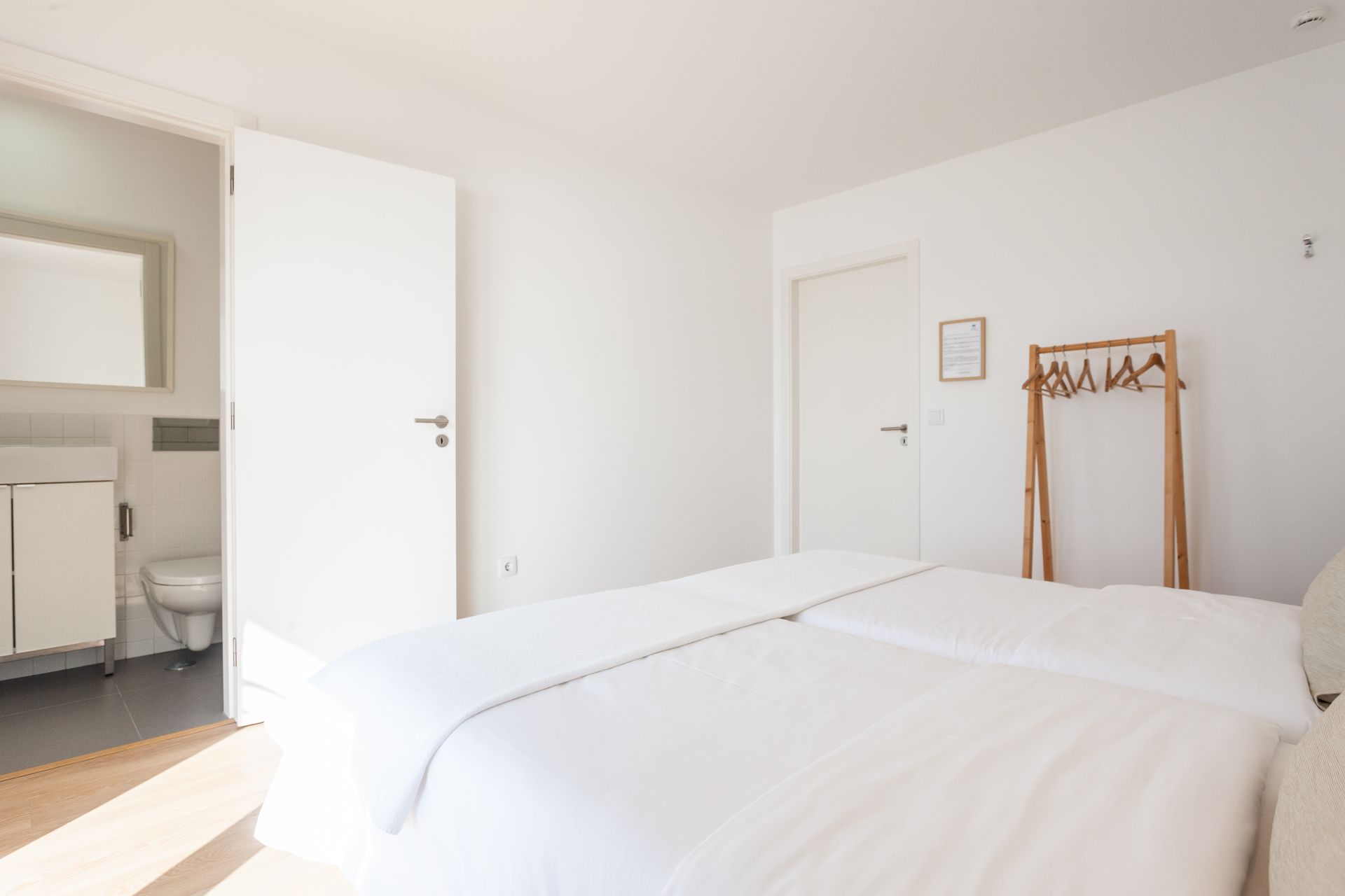 a bedroom with a bed , toilet , mirror and clothes rack .