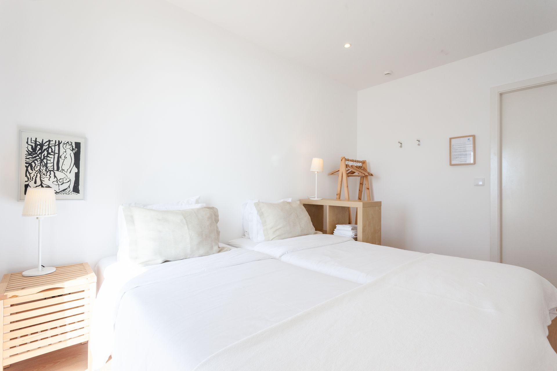 a bedroom with two beds , a nightstand , a lamp and a picture on the wall .