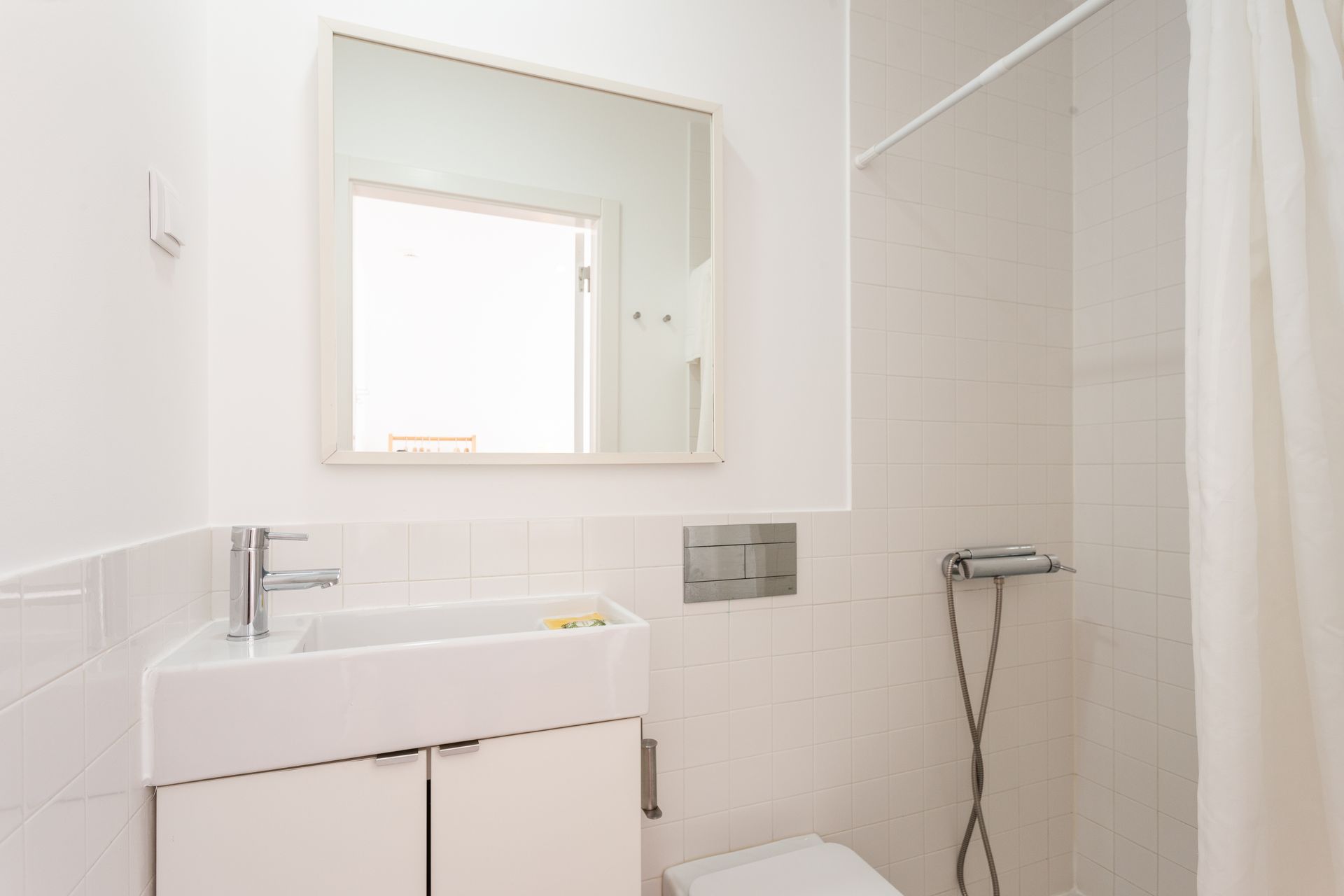 a bathroom with a sink , toilet , mirror and shower .