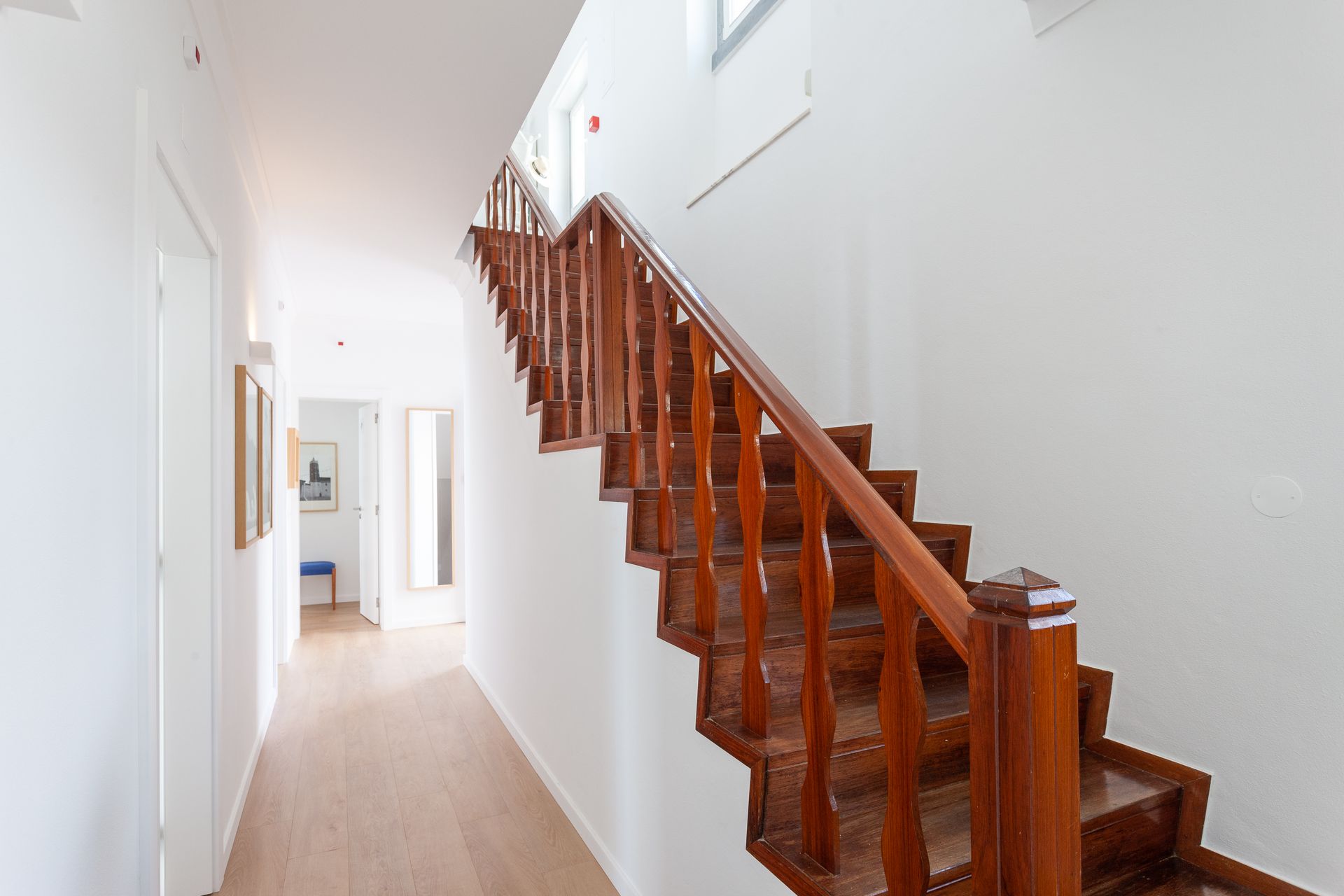 a long hallway with a wooden staircase leading up to the second floor .