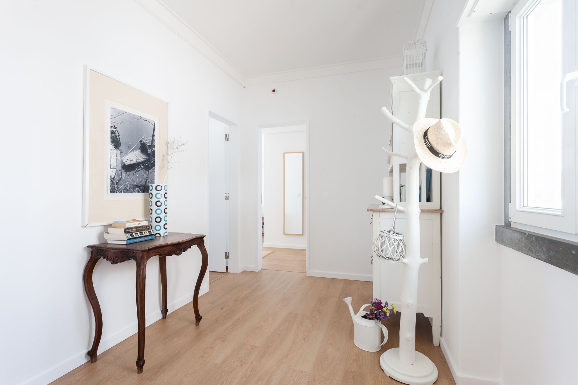a hallway with a table and a hat rack .