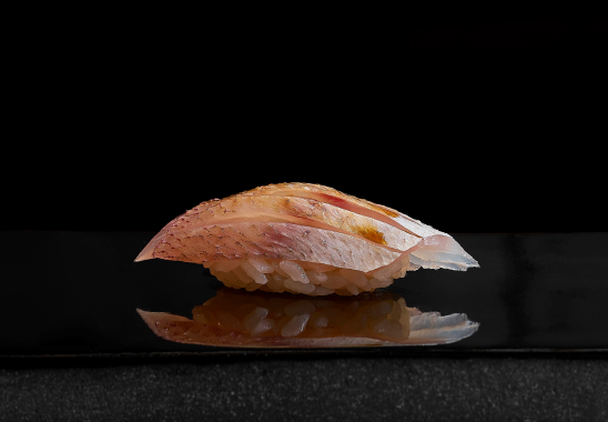 A close up of a piece of sushi on a black plate.