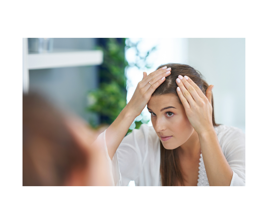 a woman is looking at her hair in the mirror .