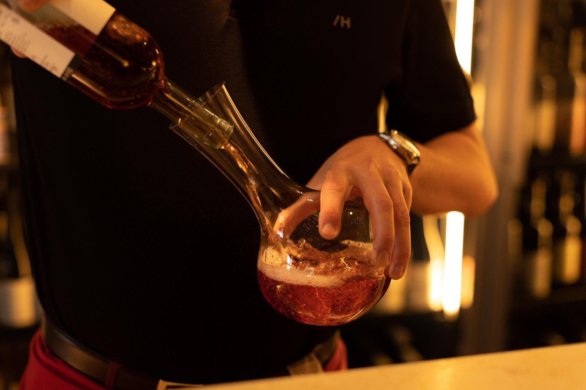 Un homme verse une bouteille de vin dans un verre.