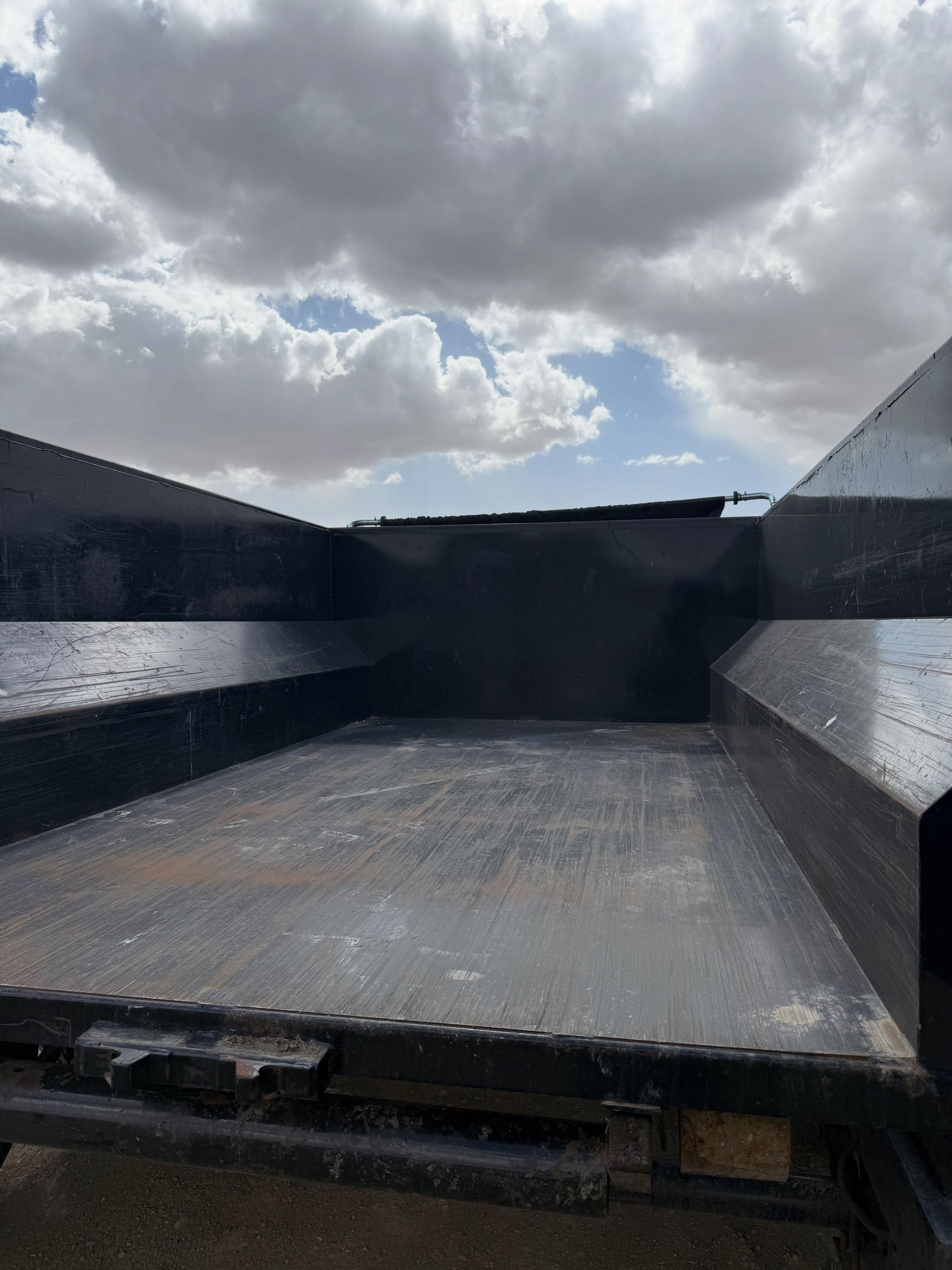 Empty industrial dumpster under a cloudy sky