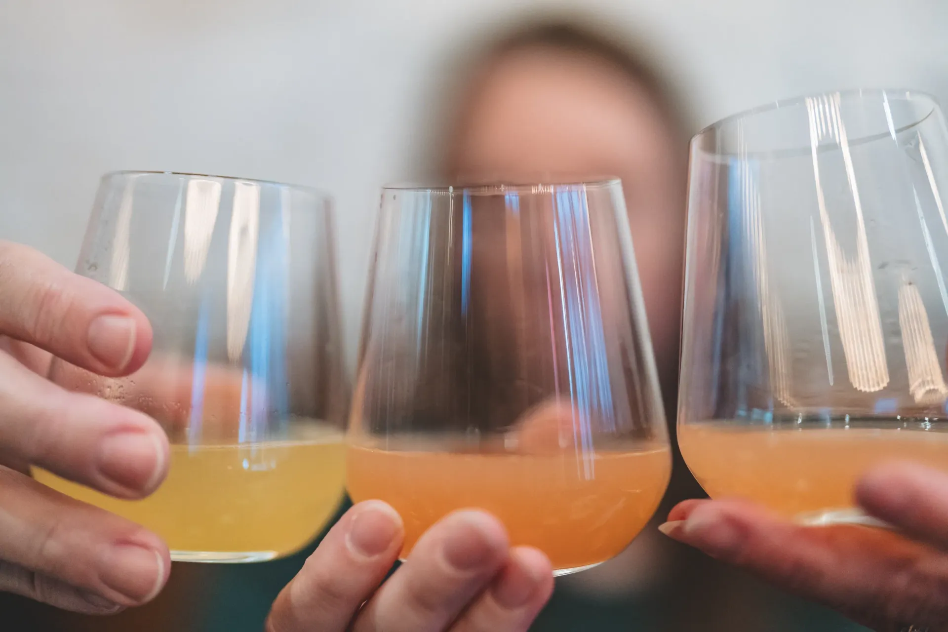Friends toasting drinks at a brunch table, laughing. Food and mugs are present.