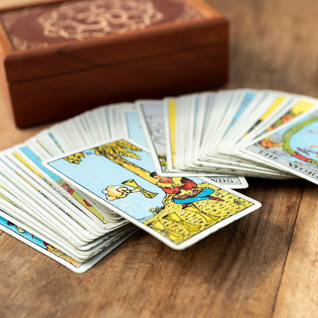 Tarotkaarten uitgespreid op een houten ondergrond met een decoratieve houten doos op de achtergrond.