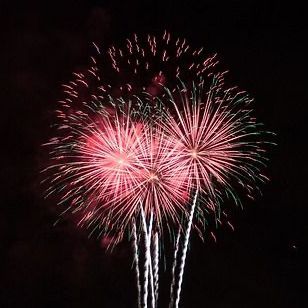 Rode en groene vuurwerkpijlen knallen tegen een donkere nachtelijke hemel.