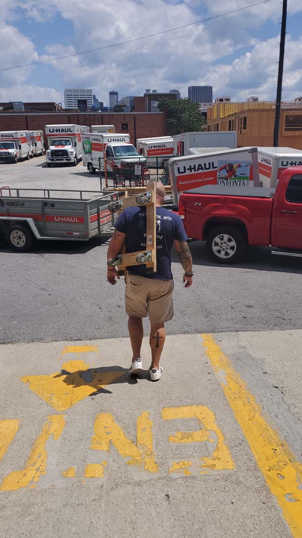 Man carrying a wooden structure, walking toward an 