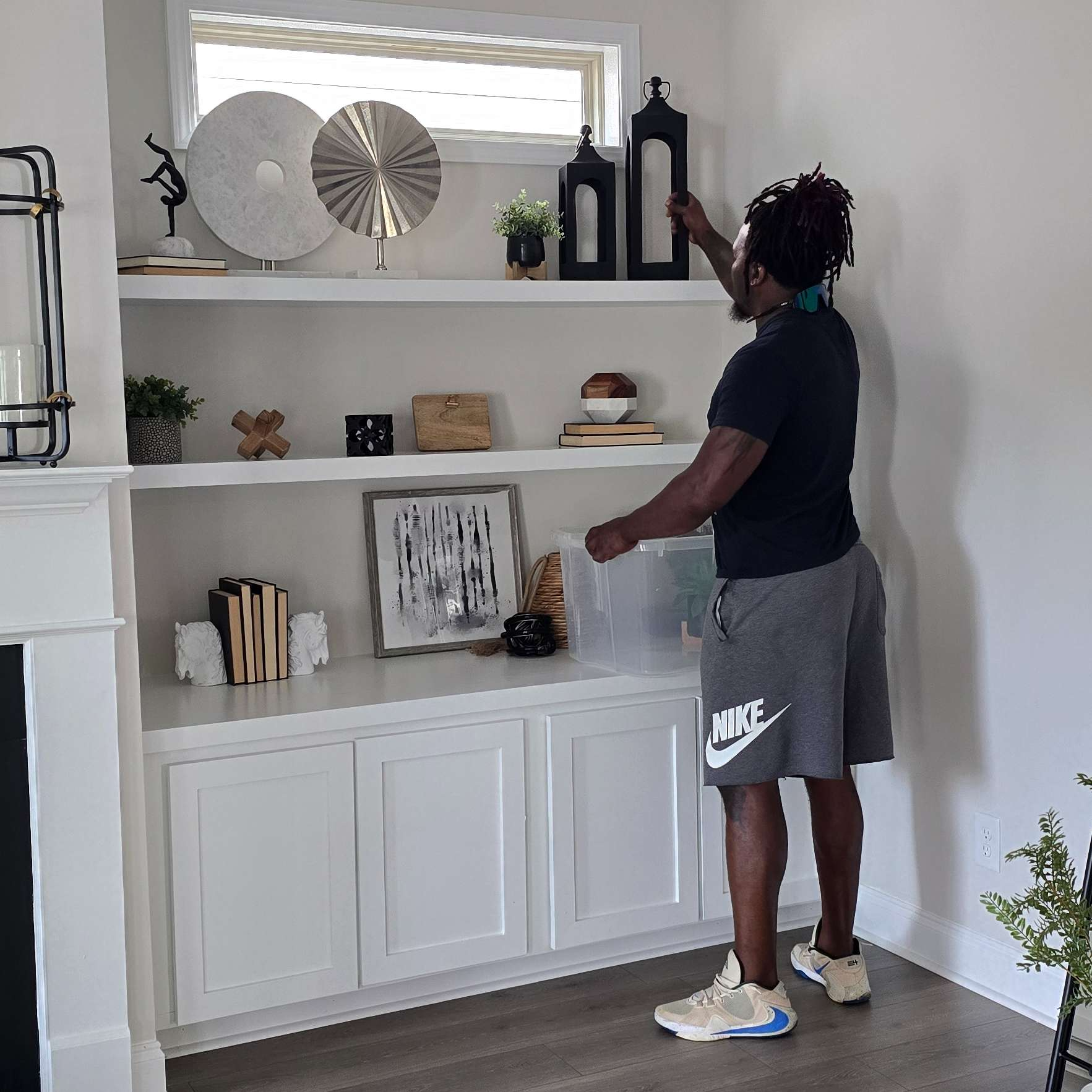 Person arranging decorations on white built-in shelves.