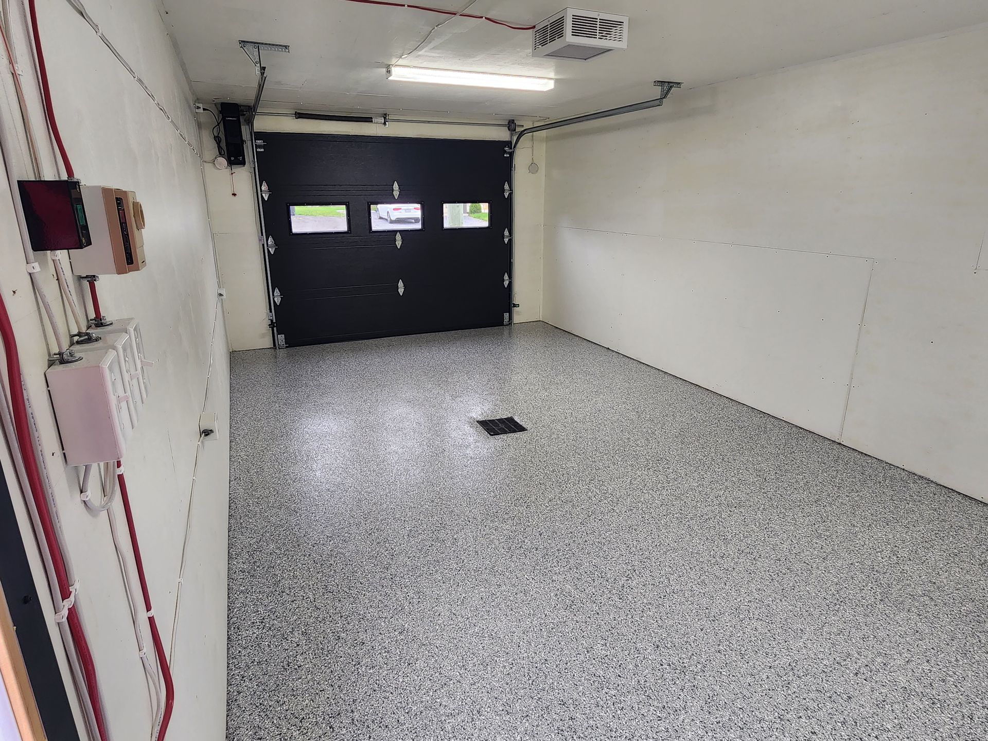 Un garage vide avec une porte de garage noire et un mur blanc