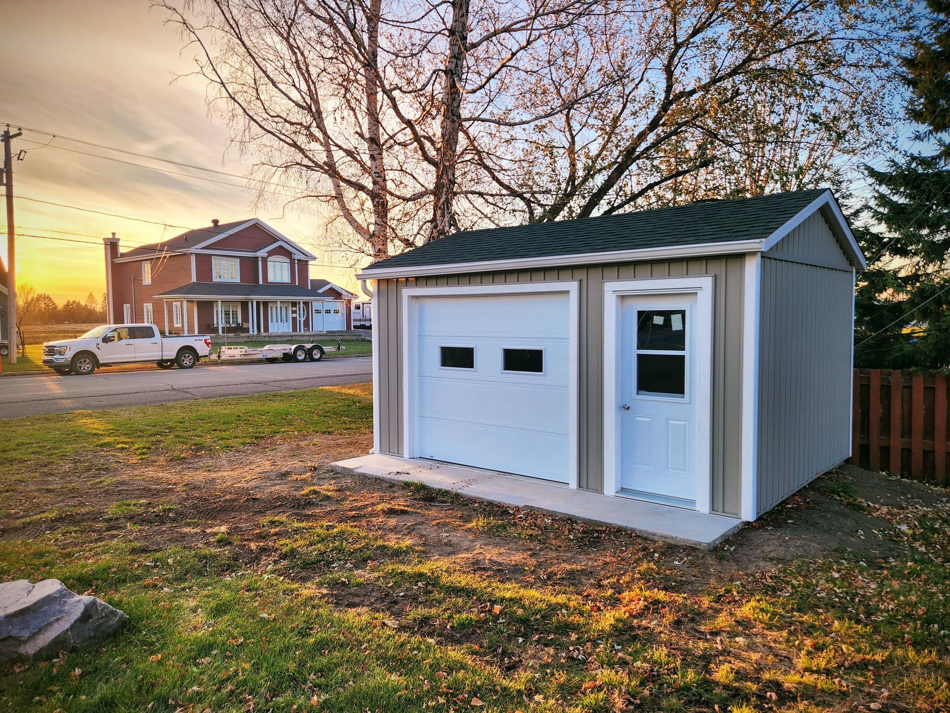 Un hangar avec une porte de garage se trouve dans l'arrière-cour d'une maison.