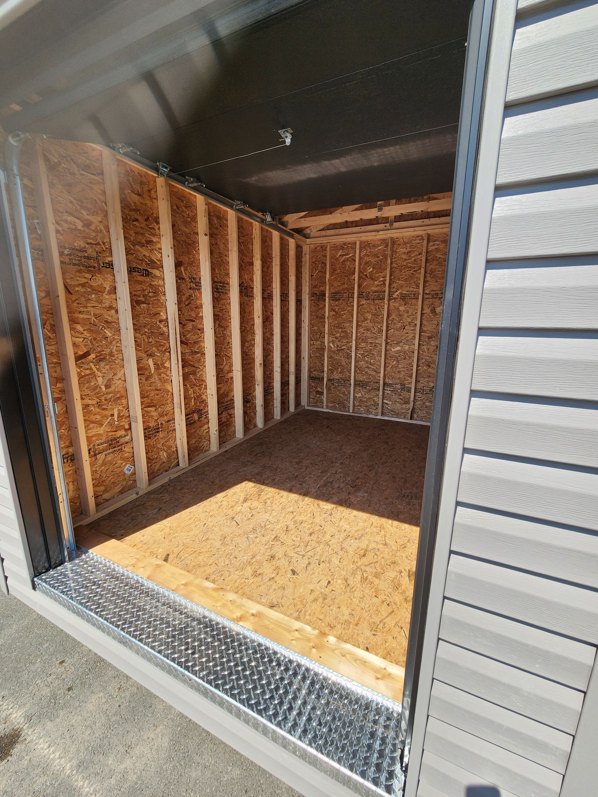 Un hangar avec une porte ouverte et un plancher en bois.