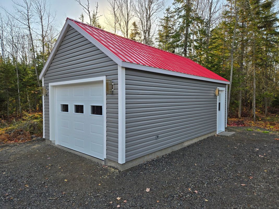 Un garage avec un toit rouge et une porte blanche.