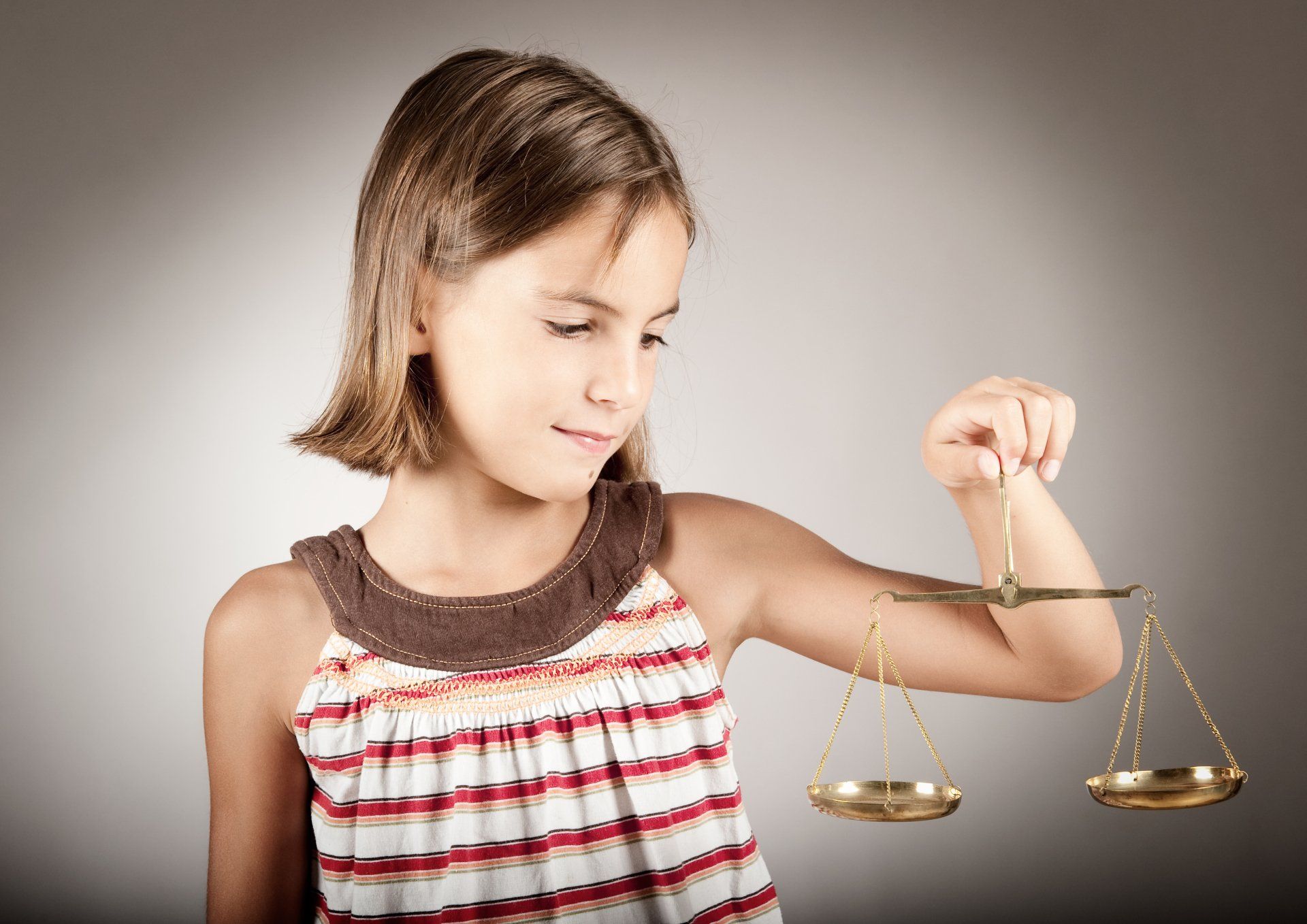 Une jeune fille tient une balance à la main.