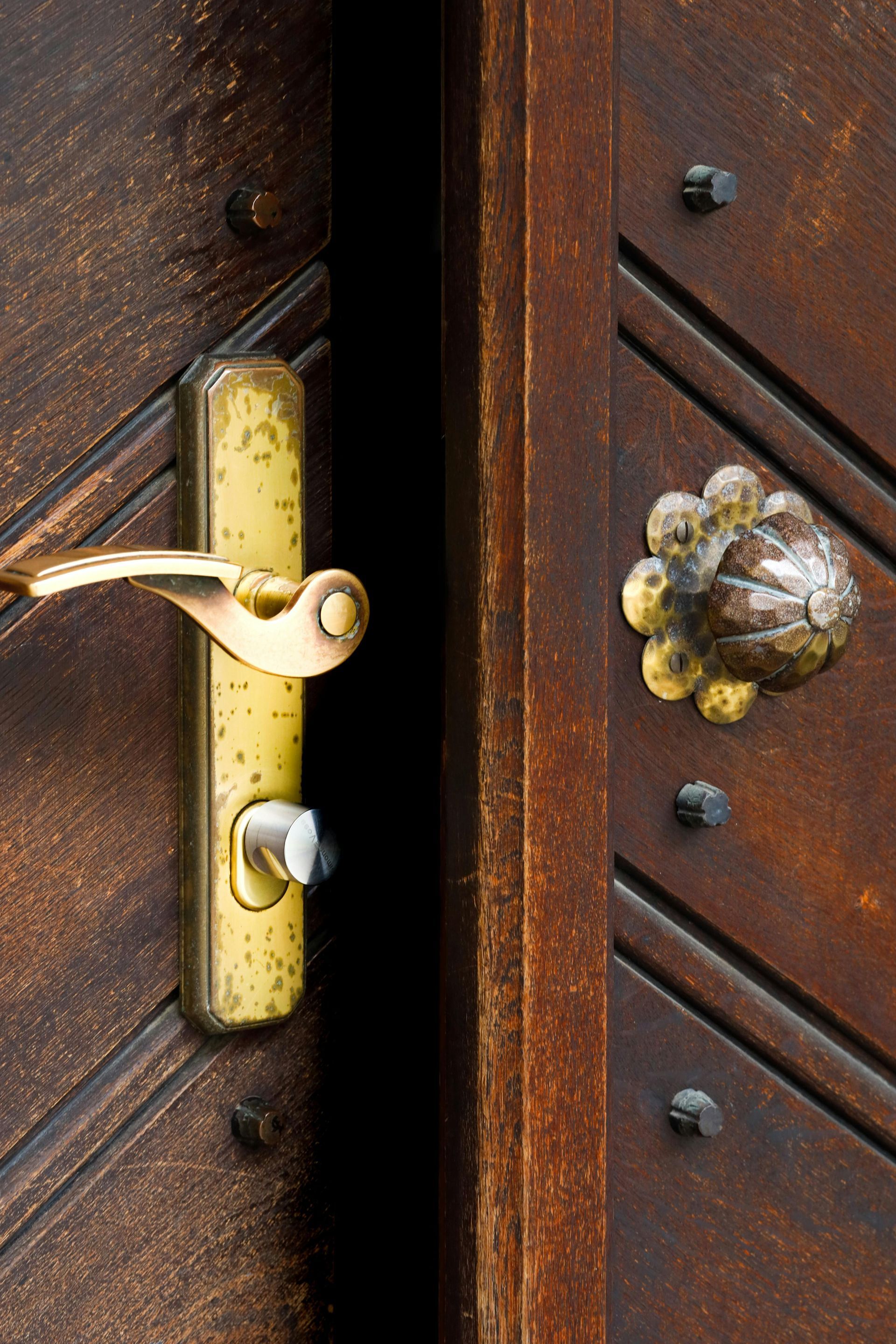 Close-up of a brass door latch and knob on a dark wooden door.