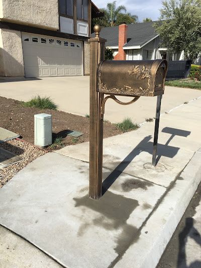 A mailbox is sitting on the sidewalk in front of a house