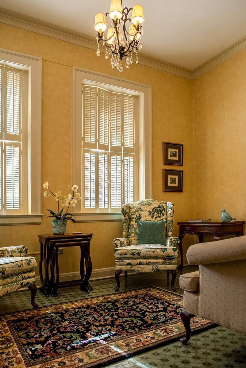 A living room with two chairs a rug and a chandelier