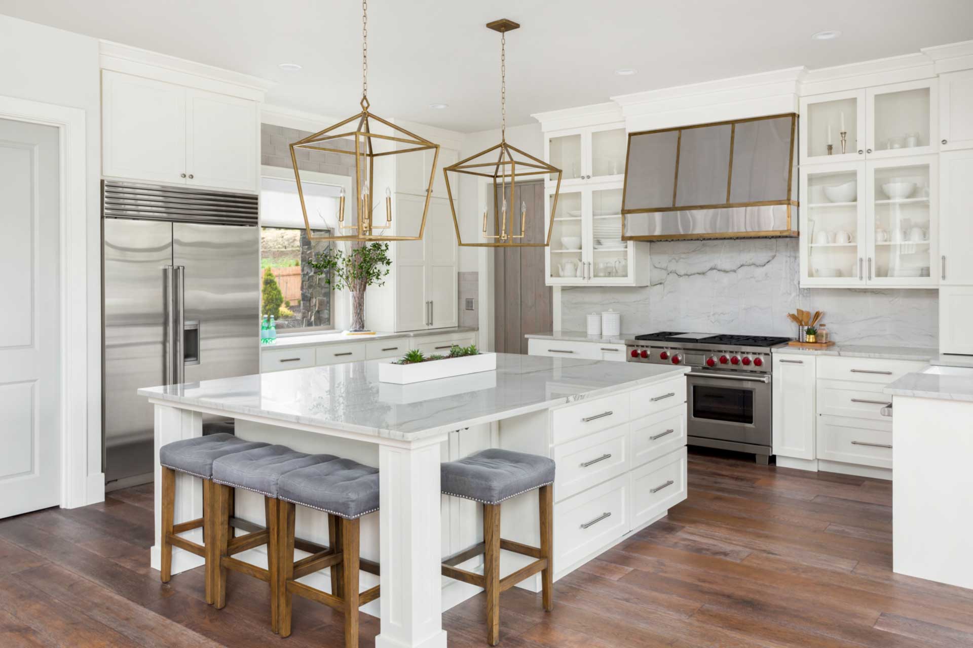 A kitchen with white cabinets , stainless steel appliances , and a large island.