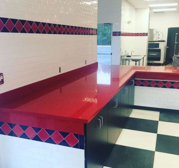 A kitchen with a red counter top and black and white checkered floor
