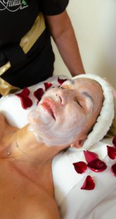 Persona que recibe un tratamiento facial con aplicación de crema, con los ojos cerrados y llevando un gorro para el cabello.
