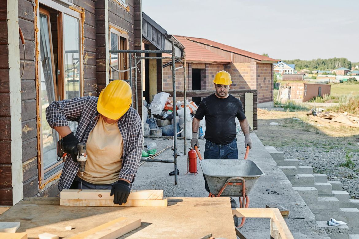Two construction workers are working on a house under construction.