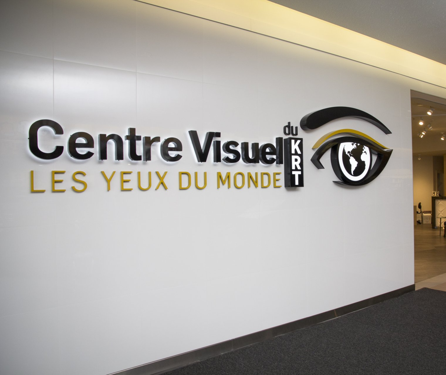 Enseigne pour « Centre Visuel du KRT », un centre de vision, avec des lettres noires et dorées et un logo en forme d'œil.