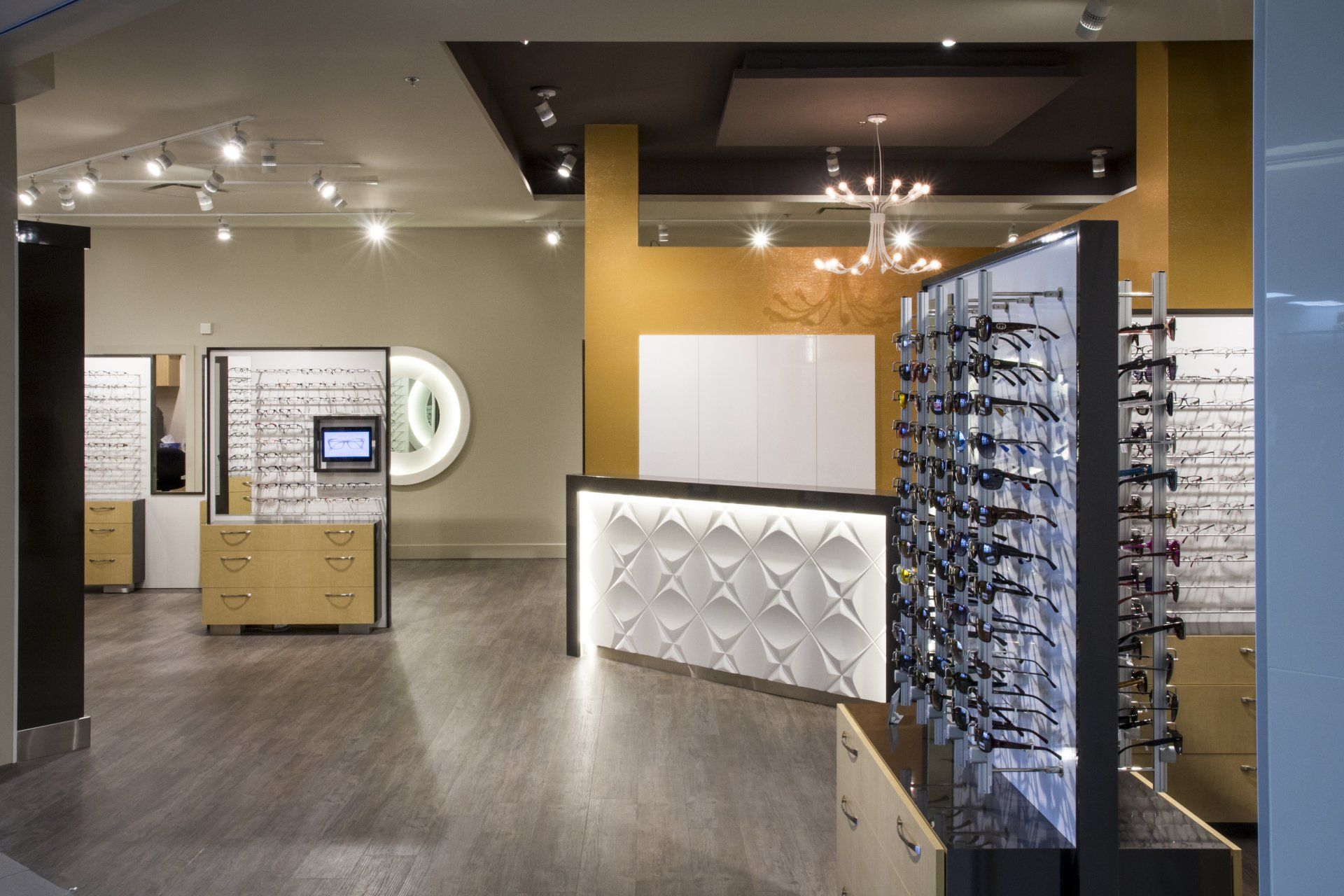 Intérieur d'un magasin d'optique avec présentoirs à lunettes, comptoir d'accueil et décor moderne.