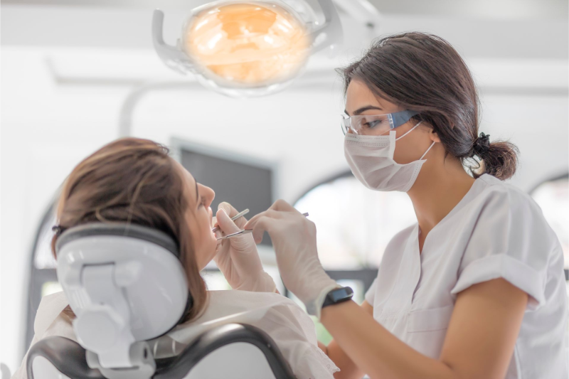 Dentist wearing a mask examines a patient in a bright dental clinic