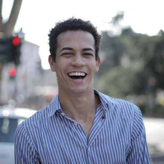 Smiling person in a blue striped shirt outdoors on a city street