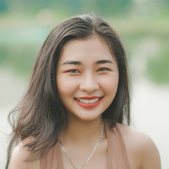 Smiling woman with shoulder-length dark hair in a soft-focus outdoor portrait