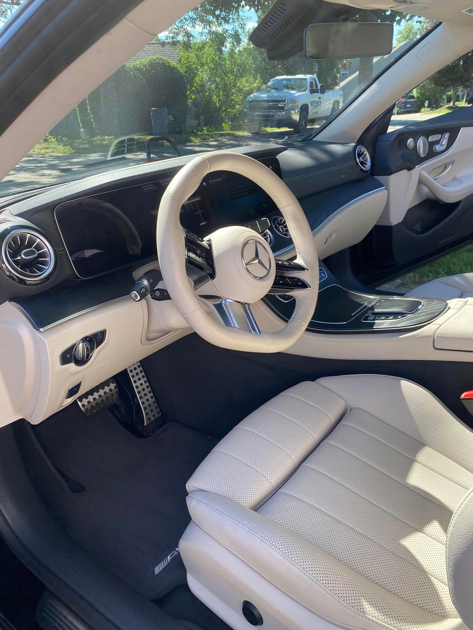 Luxury Mercedes interior with beige leather seats, dashboard, and steering wheel, viewed from the open driver’s door