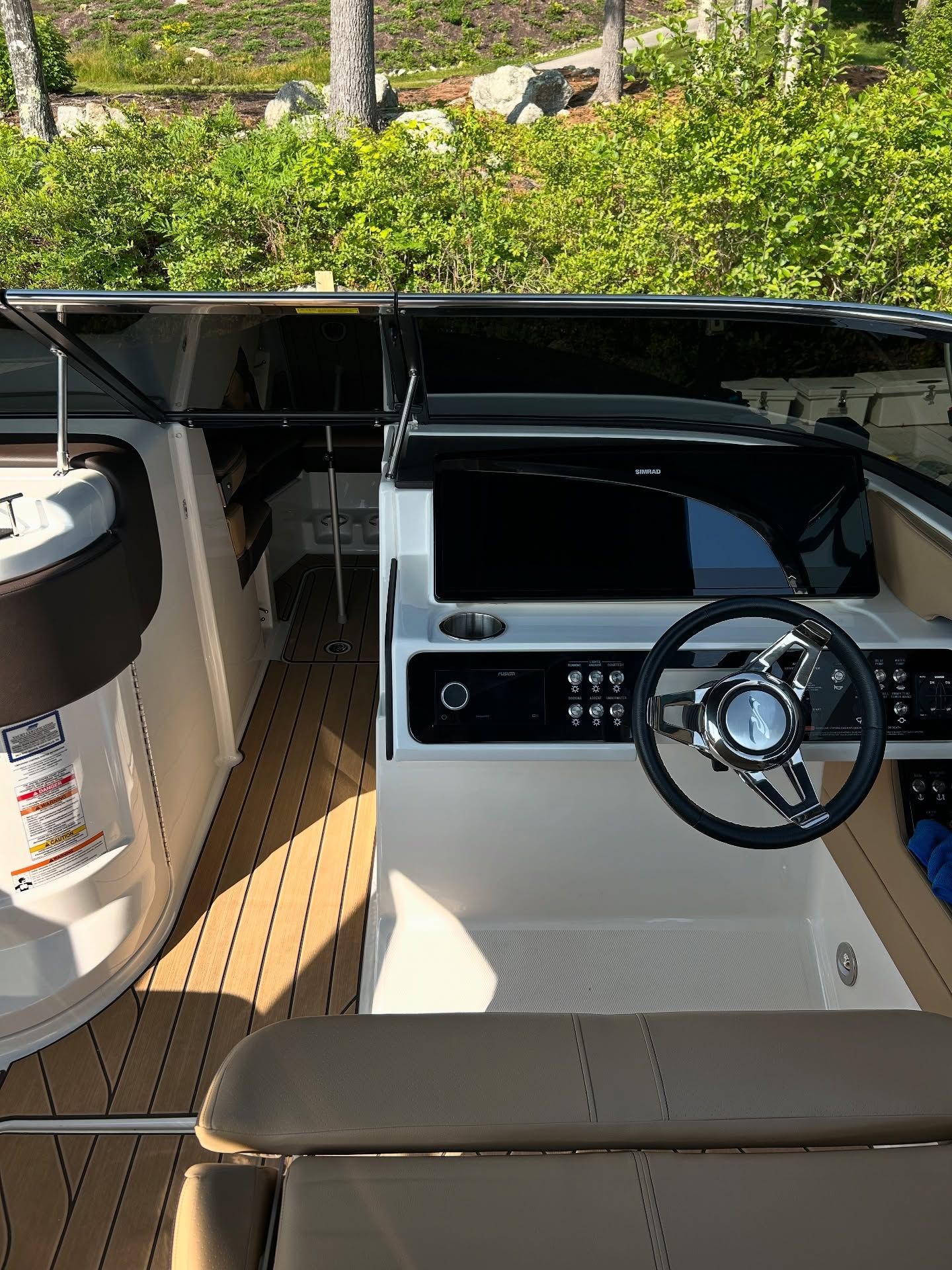 Boat helm with steering wheel and dashboard under a canopy, viewed from the cockpit.
