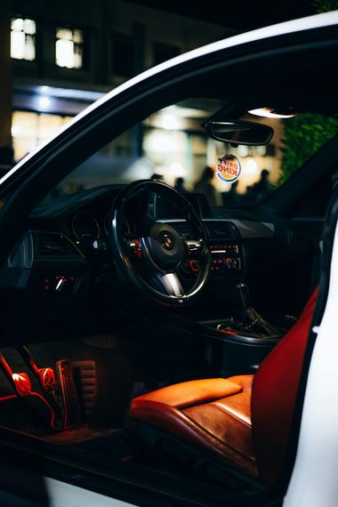 Open car door showing a red-lit luxury car interior at night