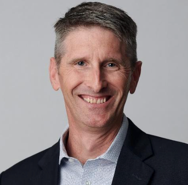 A man in a suit and shirt is smiling for the camera.