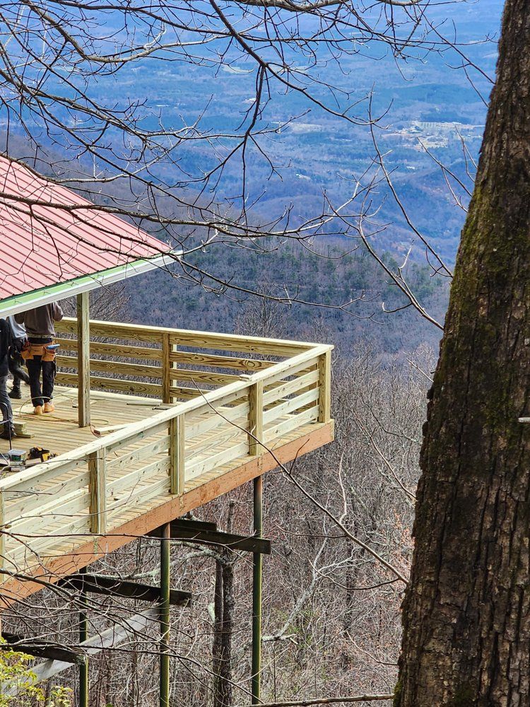 Wooden observation deck with red roof, overlooking a mountain range. People stand on deck.
