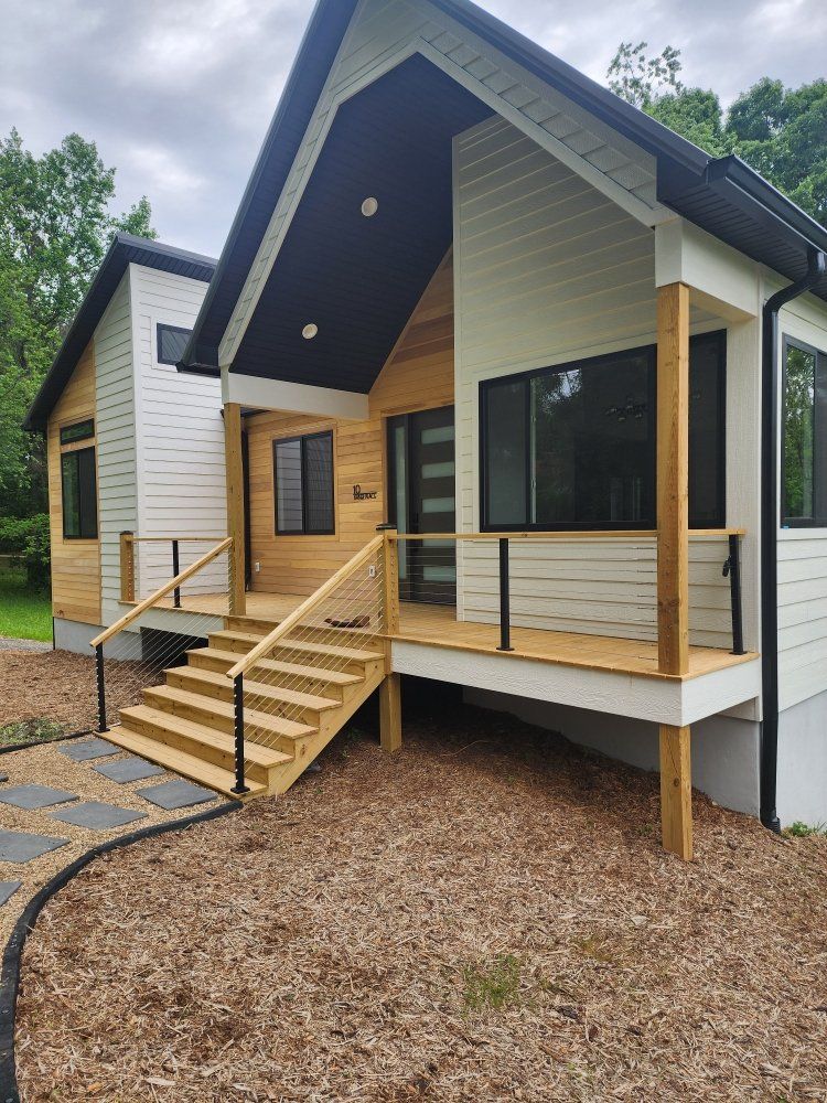Modern house with wood and white siding, front porch, and black accents.