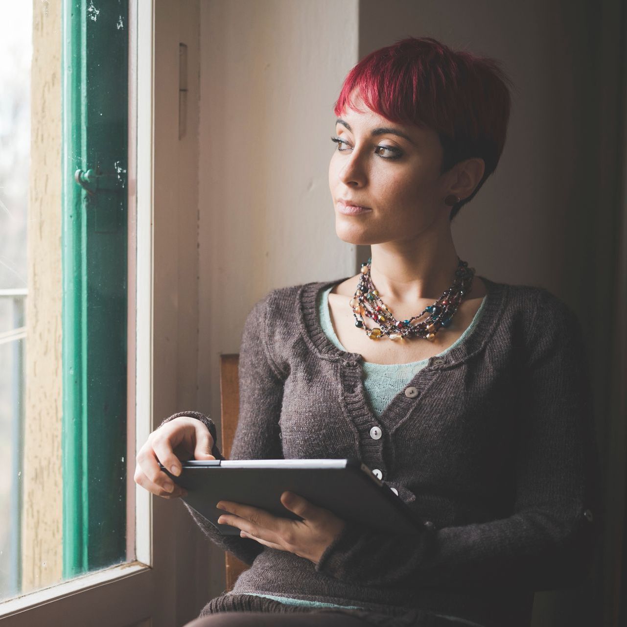 A woman wearing glasses is holding a pen to her mouth.