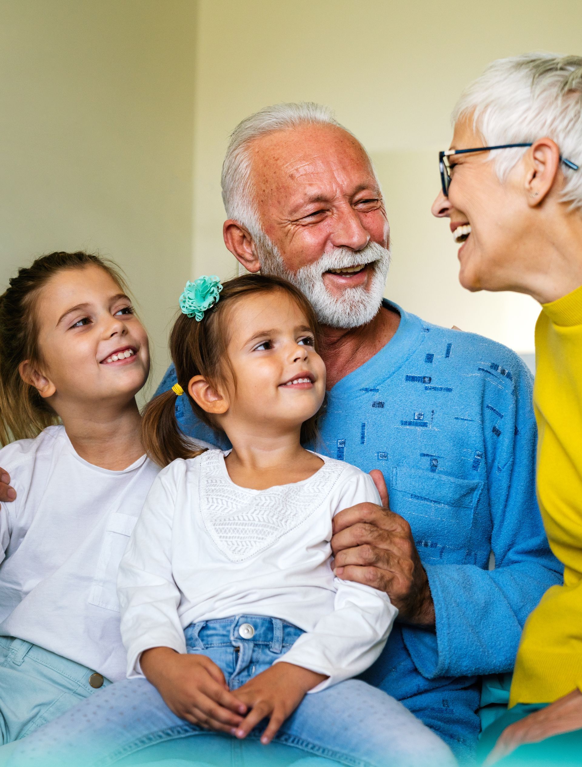 Grandparents smiling with two young girls, indoors.