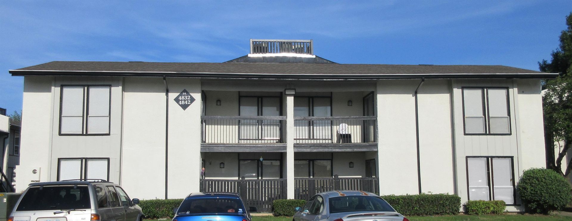 A white apartment building with cars parked in front of it