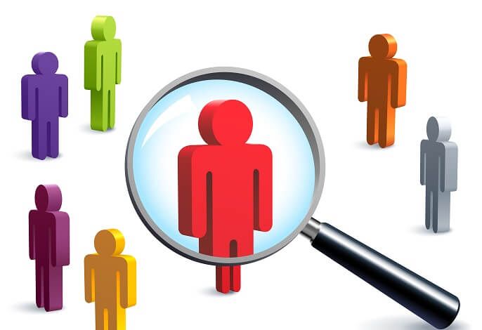 Magnifying glass highlighting a red human figure among a group of other figures