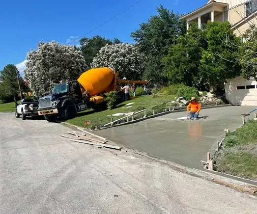 Concrete mixer truck and construction workers pouring a new concrete driveway