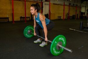 A woman is lifting a barbell in a gym.