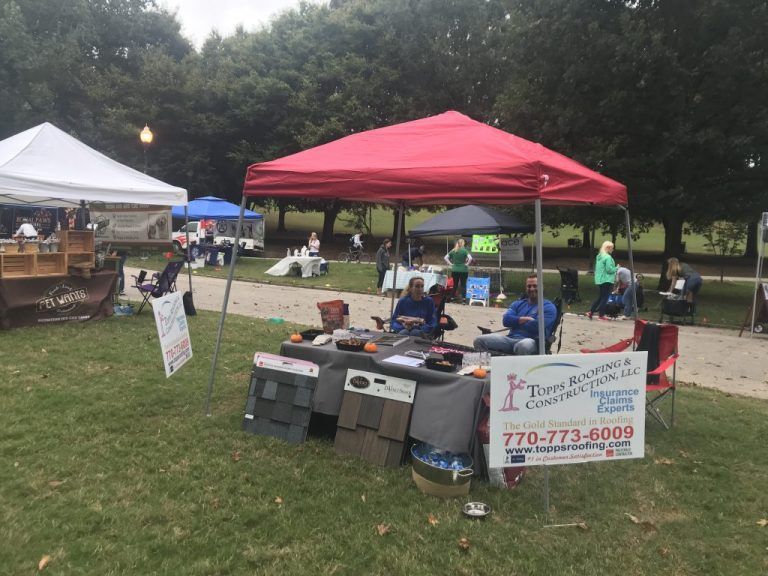 A red pop-up tent at an outdoor event featuring a Town & Country Construction display and information booth.