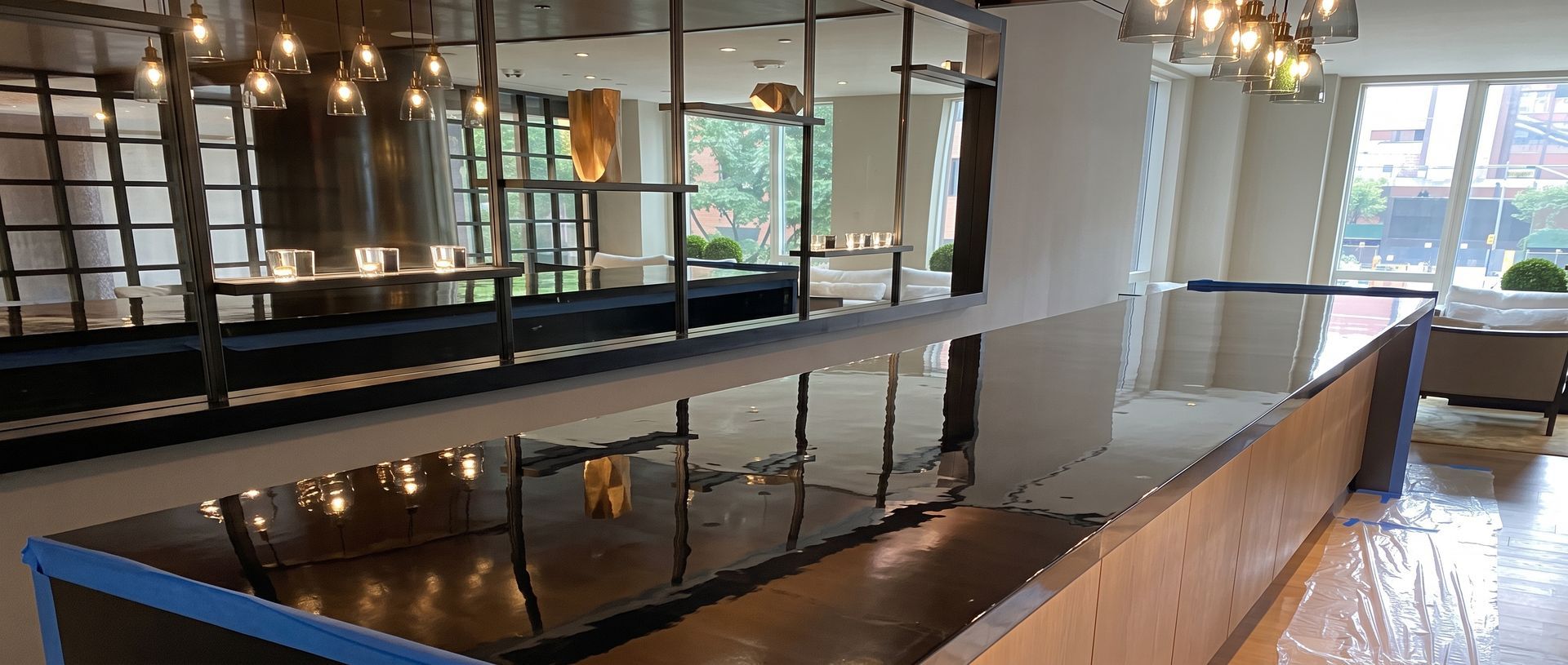 Modern open-plan dining area with long black tables, pendant lights, and large windows