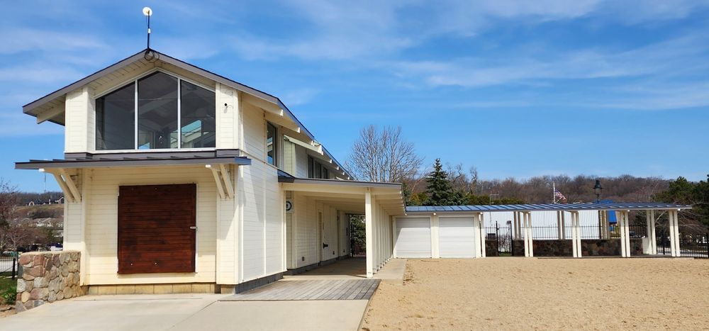 Small white two-story house with a sand-covered yard under a blue sky