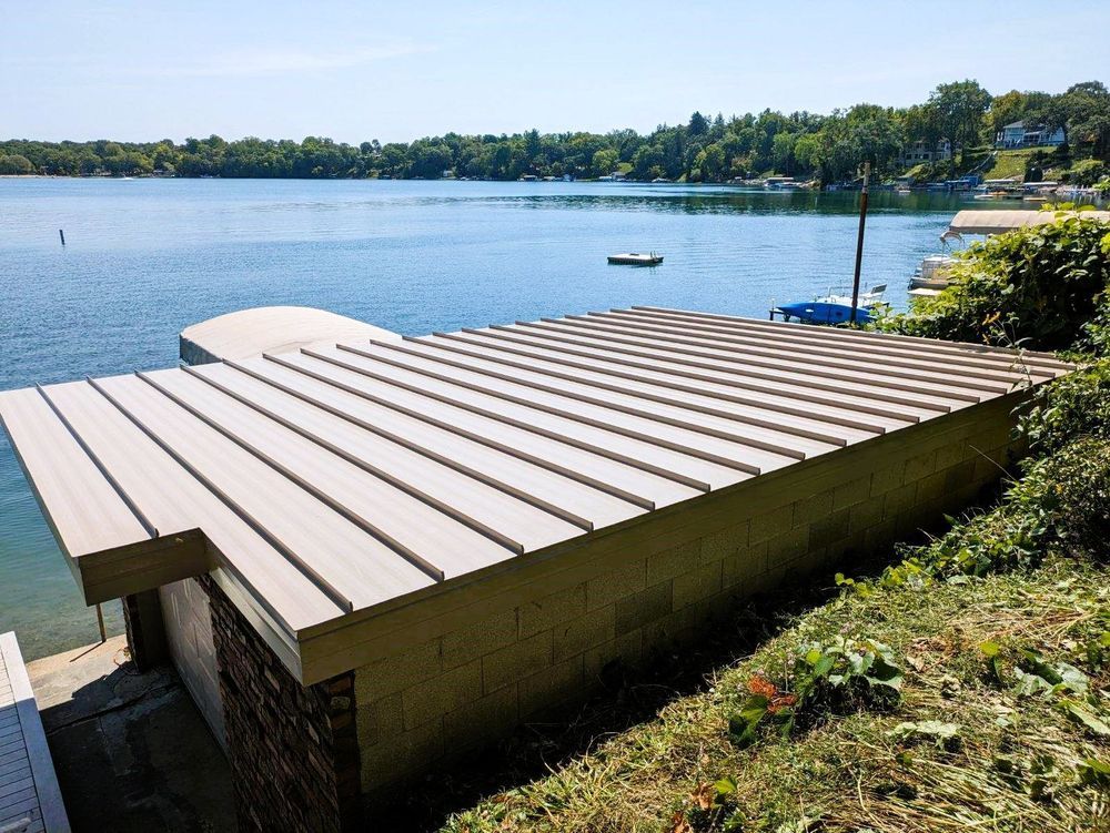 Wooden dock extending into a calm blue lake with trees and houses along the shore