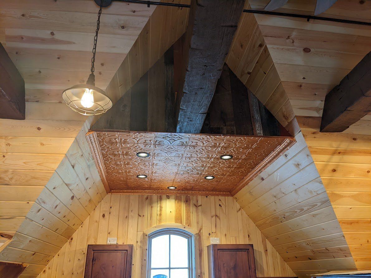Wood-paneled attic interior with a hanging light and a triangular skylight above a window
