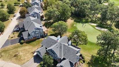 Aerial view of suburban townhouses beside a green lawn and trees